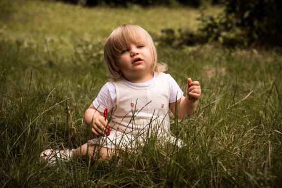 Natürliches Kinderportrait in Kassel - verträumtes Kind sitzt auf einer grünen Wiese.