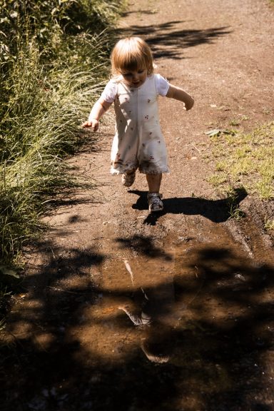 Lebendige Kinderfotografie in Kassel - Kind läuft voller Freude auf eine Pfütze zu.